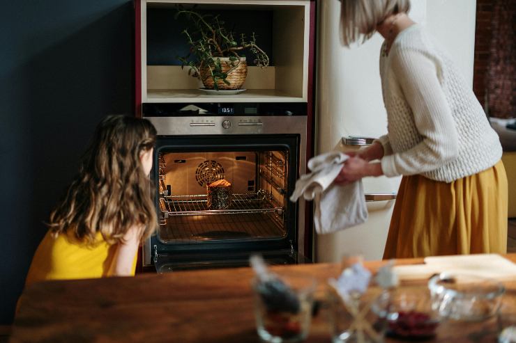 Donna e bambina controllano il forno acceso